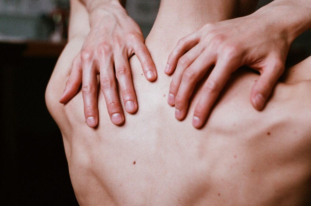 Aesthetic close-up shot of man's hands placed on his bare back, creating a calming and contemplative image.
